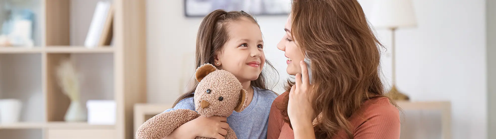 Mother talking on the phone while sitting on the couch with her daughter