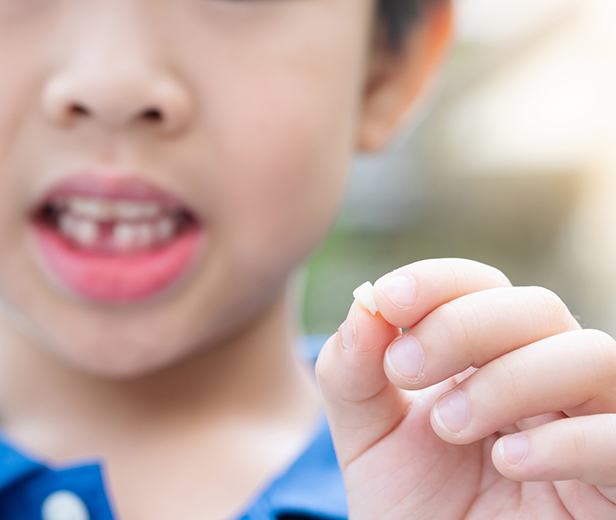 Child holding their newly lost tooth