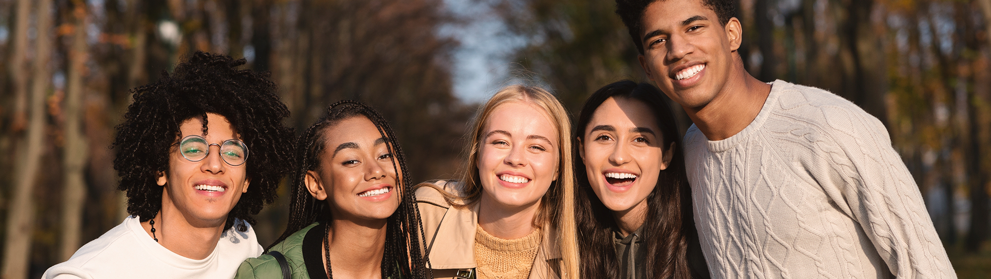 Group of teenagers smiling with a forest in the background
