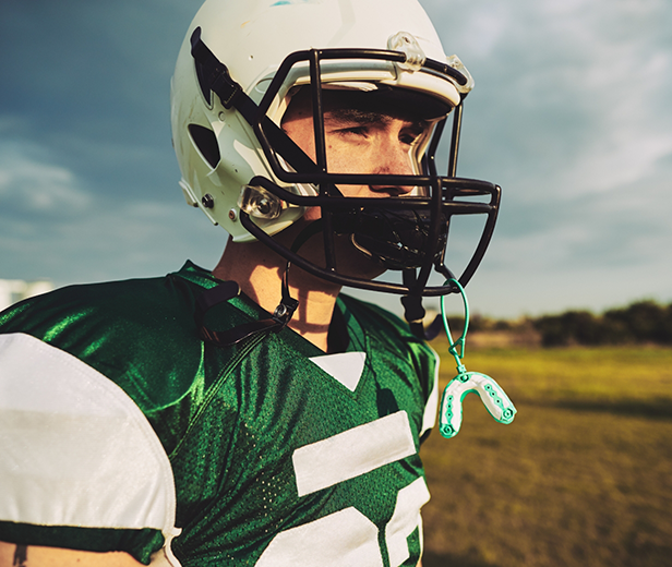 Football player with a mouthguard attached to their helmet
