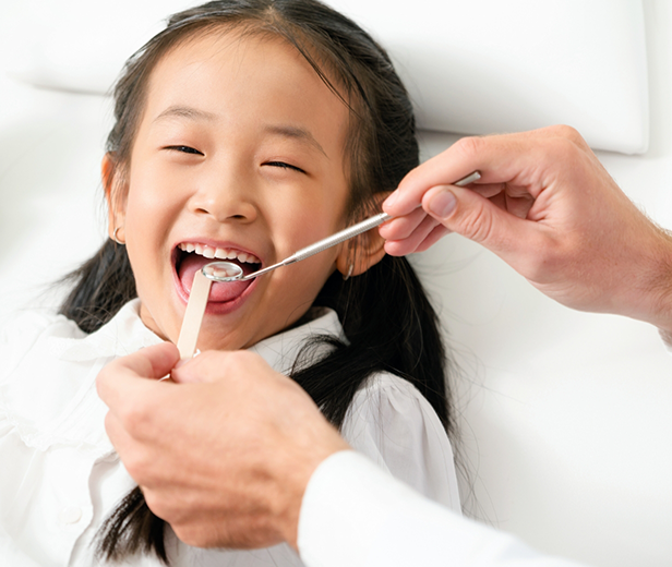 Young girl having her teeth examined by her pediatric emergency dentist